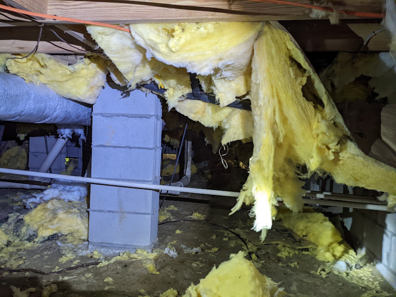Sagging fiberglass batts hanging loose between floor joists in a crawlspace