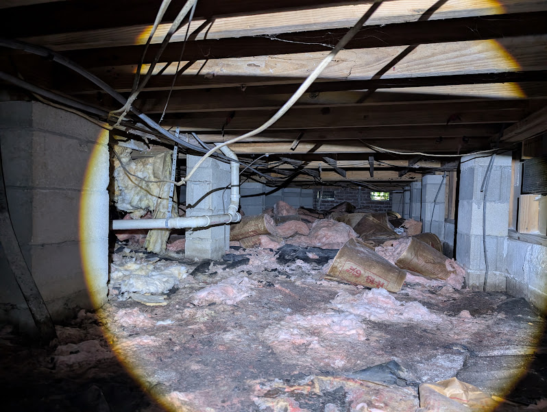 Bagged insulation and debris staged for removal during a crawlspace cleanout