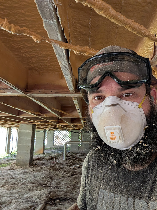 Intercoastal Crawlspace technician in goggles and a respirator working under a home